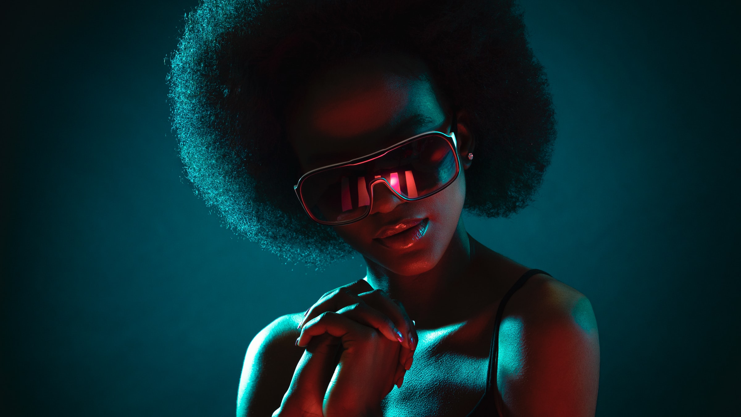A black woman under blue light with futuristic sunglasses